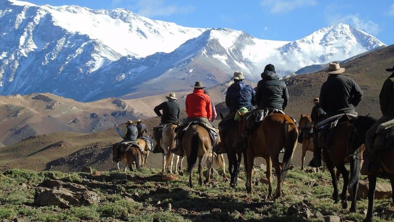 Riders on horseback looking across the Andes during a trans-Andes trek